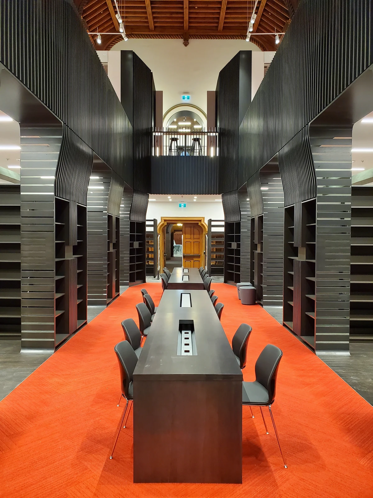 Library shelving and a long central study table beneath an open upper level