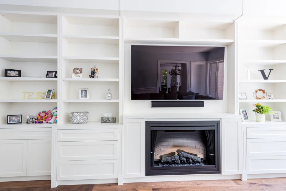 White built-in bookcases and lower cabinets on either side of a fireplace
