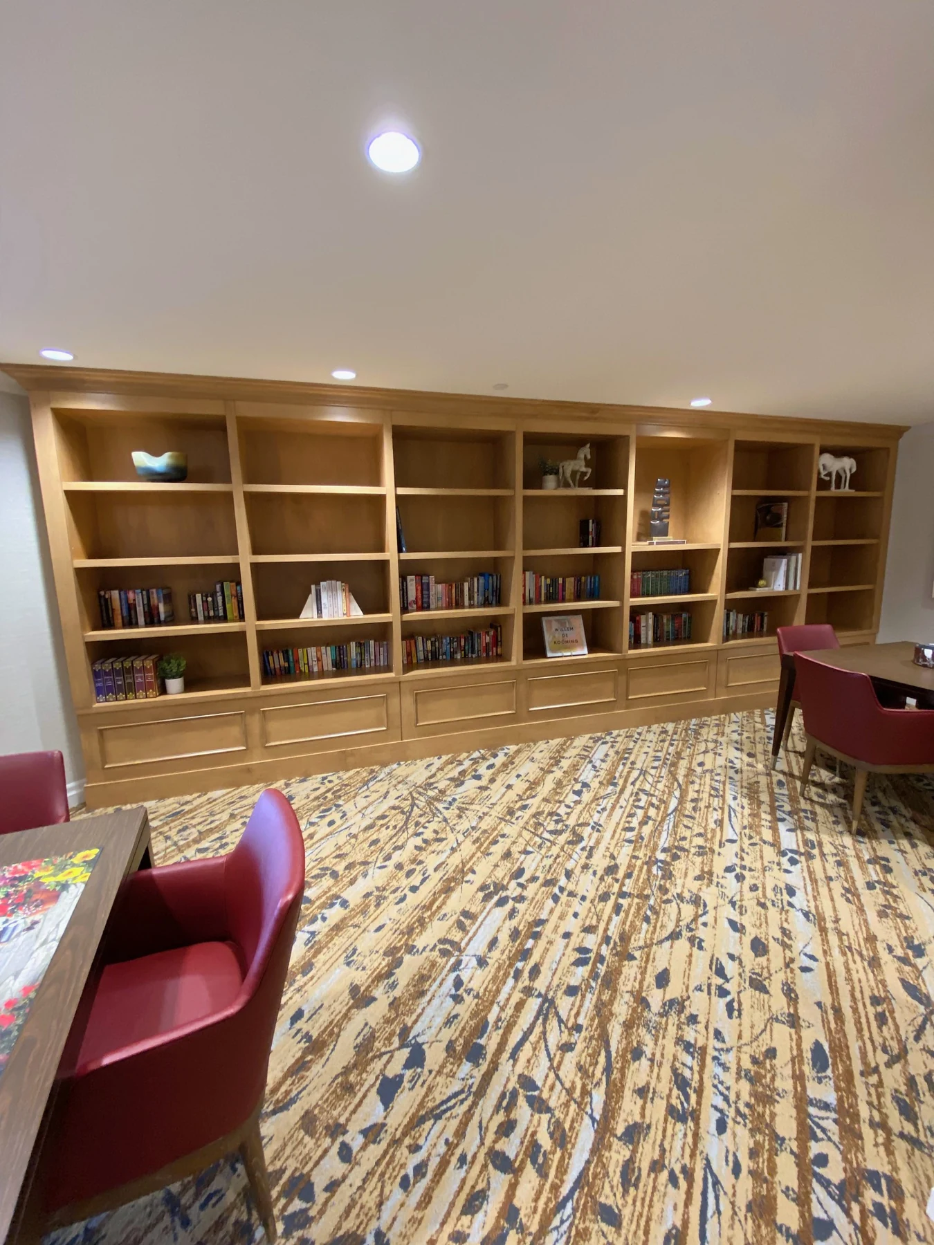 A built-in library wall with open shelves above panelled base cabinets at Amica Whitby.